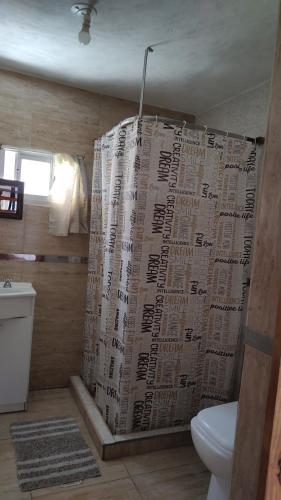 a bathroom with a newspaper shower curtain with a toilet at Dúplex para 4 San Luis in Barranca Colorada