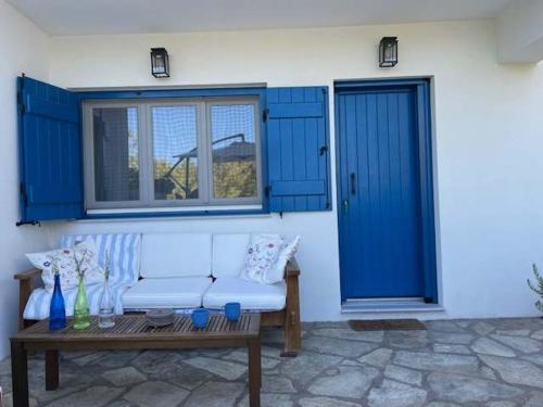 a white couch sitting on a patio with blue doors at Charming Spetses Studio with Outdoor Space in Spetses