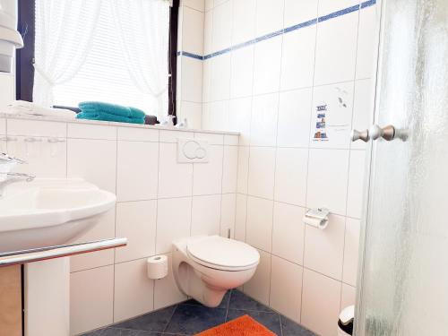 a white bathroom with a toilet and a sink at Haus Ausreißer 2 - Hafennest in Bensersiel