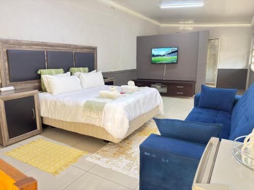 a bedroom with a large bed and a blue couch at Palm Guesthouse in Zeerust