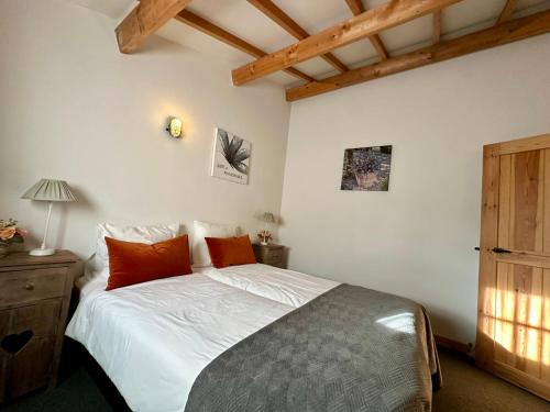 a bedroom with a bed with white sheets and red pillows at Erfgoed & Logies Den Heijkant in Moergestel
