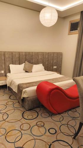a bedroom with a large bed with a red seat at شقق أبهى المضياف الذهبية للشقق المخدومة in Abha