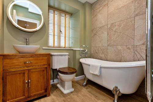 a bathroom with a tub and a toilet and a sink at Finest Retreats - The Kiln in Bamburgh