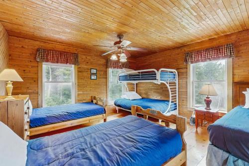 a bedroom with three bunk beds in a log cabin at Chez Normand in Jefferson