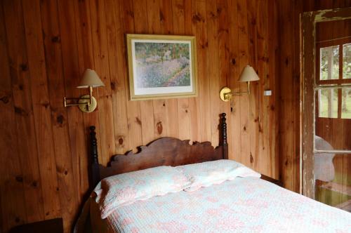 ein Schlafzimmer mit einem Bett mit einer Holzwand in der Unterkunft Aldeia Santuario das Aves in Tavares