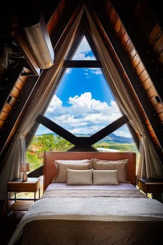 a bed in a room with a large window at Cipó Cabanas in Santana do Riacho