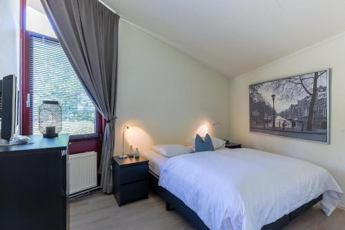 a bedroom with a white bed and a large window at Aquaronde 093 in Lemmer