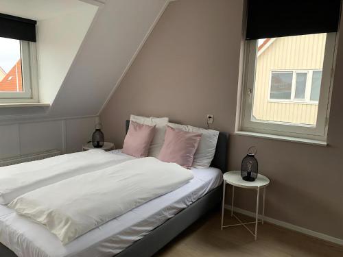 a bedroom with a bed with white sheets and pink pillows at Park De Marol Grutto 8 in Lemmer