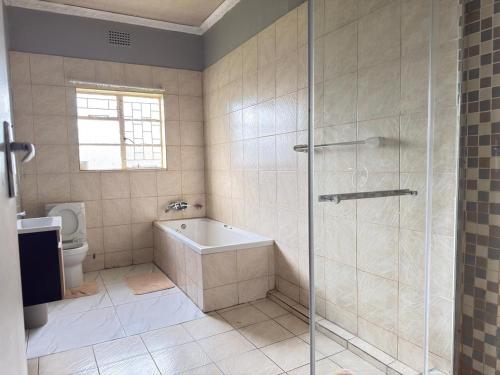 a bathroom with a shower and a tub and a toilet at Marico Bosveld Guesthouse in Zeerust