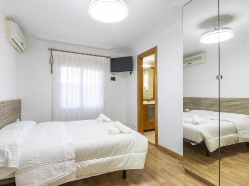 a white bedroom with two beds and a mirror at Winahost Villa Unión in Puebla de Vallbona