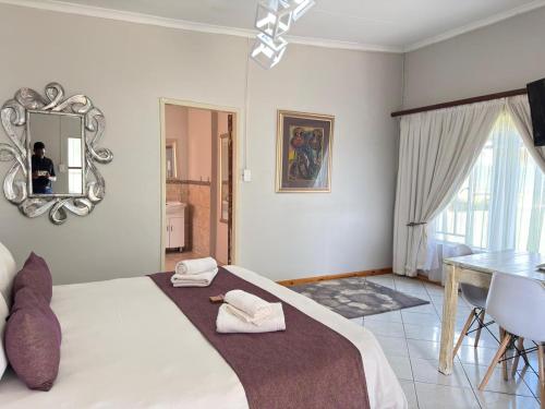 a bedroom with a bed and a table and a mirror at Marico Bosveld Guesthouse in Zeerust