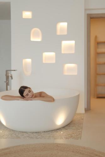 a woman laying in a bath tub in a bathroom at Gabbiano Azzurro Hotel & Suites in Golfo Aranci