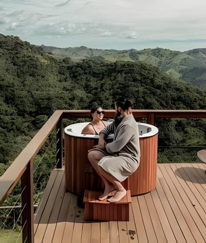 two people sitting in a hot tub on a deck at Cabana do Café - Olivais Santa Clara in Cambuí
