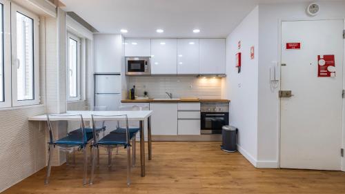 a kitchen with white cabinets and a table and chairs at Sítio do Castelo Beach in Cascais by LovelyStay in Cascais
