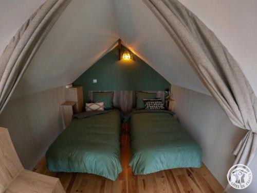 a bedroom with two green beds in a attic at L'écrin de lacoste in Chasteaux