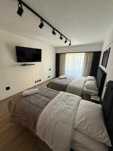 a hotel room with three beds and a flat screen tv at Hotel Sol Alphaville1505 in Barueri
