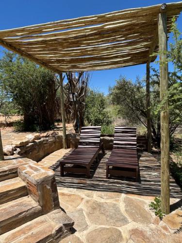 two lounge chairs on a wooden deck with a pergola at BellaTiny Campsite with camping cabin for 4 in Windhoek