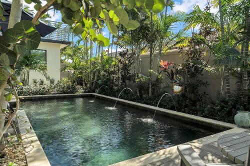 a swimming pool in a garden with two fountains at Charming Studio w Pool One Mile to Beach Pets Welcome in Lake Worth