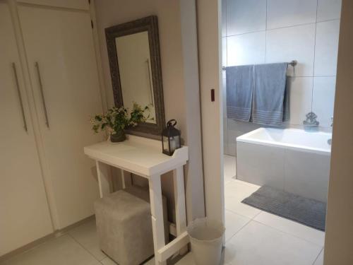 a bathroom with a sink and a mirror and a bath tub at OppiDam Gastehuis in Vanderkloof