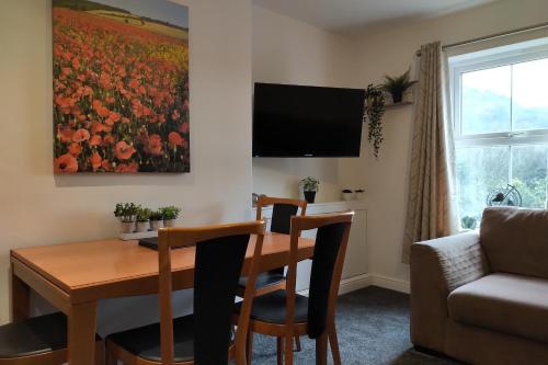 a living room with a dining room table with a painting of flowers at Oliver Wests Beautiful 2 Bedroom Sleeps 4 Apartment in Scarborough