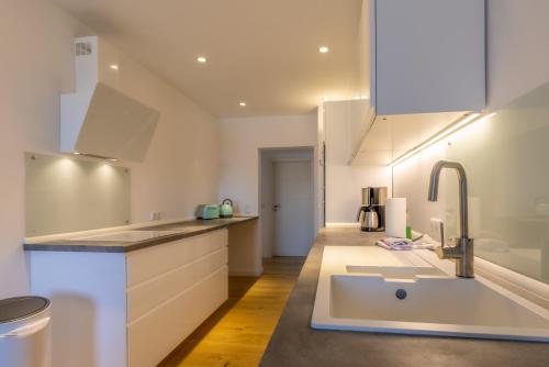 a white kitchen with a sink and a counter at Die Schlafstube - Boutiquehotel in Neuharlingersiel