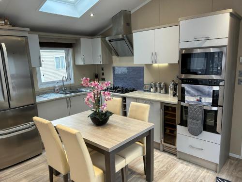 a kitchen with a table with a vase of flowers on it at Tulip 10, Oakdene Forest Park , passes included in Saint Leonards
