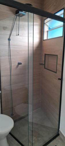 a shower with a glass door in a bathroom at Kasa Mare studios Maresias in São Sebastião