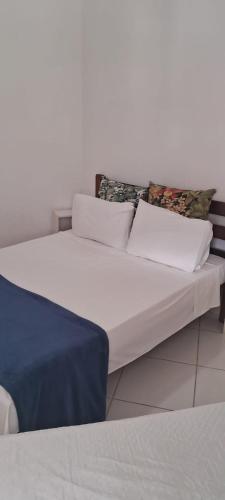 a large bed with white sheets and pillows on it at Kasa Mare studios Maresias in São Sebastião