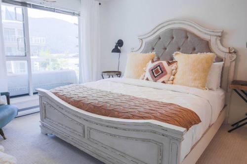 a bedroom with a white bed with pillows and a window at Lakefront Haven Mtn View Condo Steps from Beach in Harrison Hot Springs