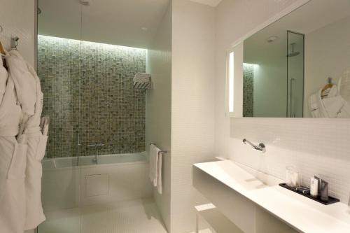 a white bathroom with a sink and a shower at Le Grand Hôtel Grenoble, BW Premier Collection by Best Western in Grenoble