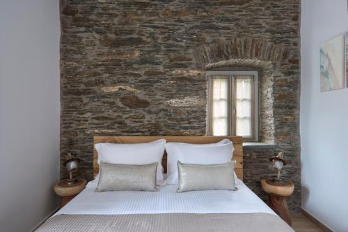 a bedroom with a brick wall and a bed with pillows at Alaia Boutique houses in Batsi