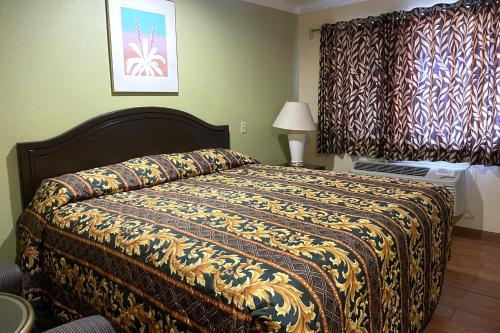 a bedroom with a bed with a blanket on it at Sun Star Inn Los Banos in Los Banos