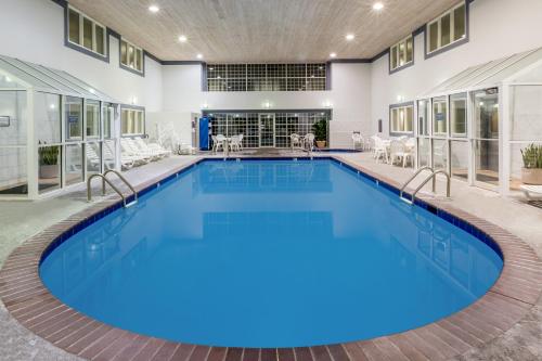 a large pool with blue water in a building at Baymont by Wyndham Des Moines Airport in Des Moines