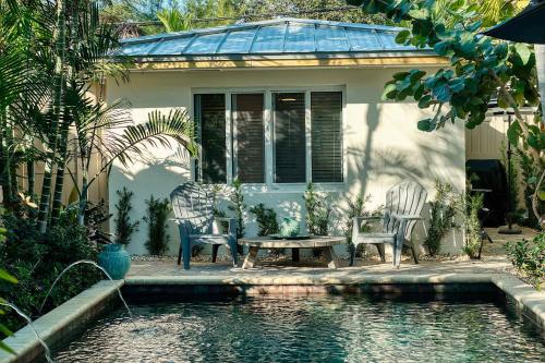 a house with two chairs and a table next to a pool at Charming Studio w Pool One Mile to Beach Pets Welcome in Lake Worth