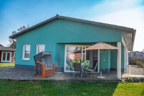 a blue house with a table and chairs and an umbrella at Bungalow Klüver in Ueckermünde