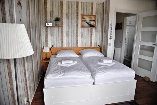 a bedroom with a bed with white sheets and a lamp at Lagunenstadt am Haff - Fewo 166 Nautilus in Ueckermünde