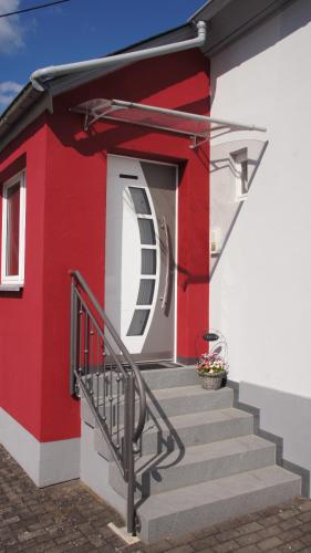 a red and white house with stairs and a door at Ferienhaus am Flaumbach in Blankenrath