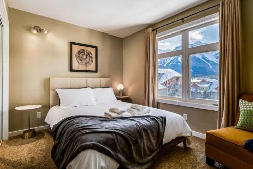 a bedroom with a bed and a large window at Stylish Mountain View Condo with Gym in Canmore