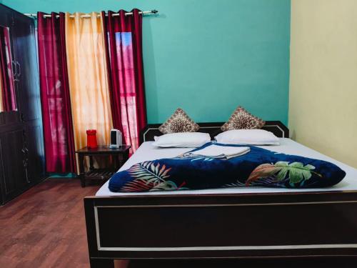 a bedroom with a bed with blue walls and colorful curtains at Corbett Bungalow Stay- Private Garden Stay Near Jim Corbett in Rāmnagar