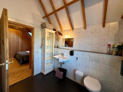 a bathroom with a sink and a toilet and a bedroom at Erfgoed & Logies Den Heijkant in Moergestel