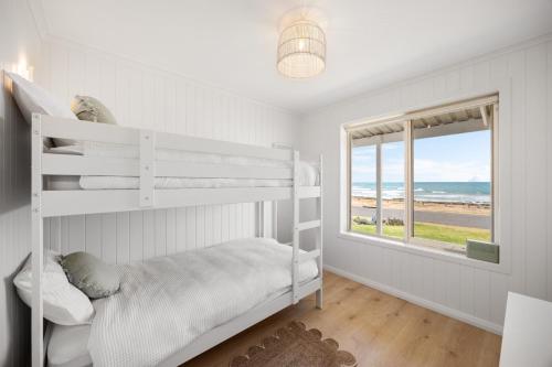 a white bedroom with a bunk bed and a window at Nest at Bashams - A Panoramic Oceanfront Sanctuary in Middleton