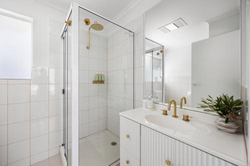 a white bathroom with a shower and a sink at Nest at Bashams - A Panoramic Oceanfront Sanctuary in Middleton