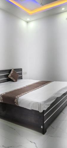 a bed in a white room with avertisementatronatronatronstrationstration at Shanti palace and restaurant Ayodhya 1500 mtr Sri Ram Mandir ,near ayodhya dham railway station in Ayodhya