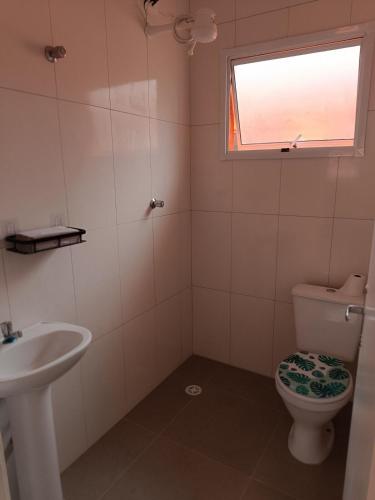 a bathroom with a toilet and a sink and a window at Boracéia Apto 1 quarto in Bertioga