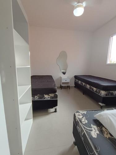 a bedroom with two beds and a mirror at Boracéia Apto 1 quarto in Bertioga