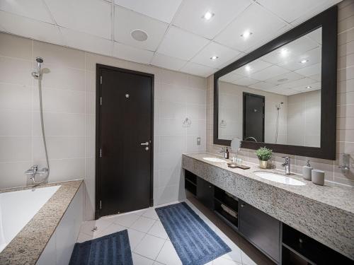 a bathroom with two sinks and a large mirror at Livin' Holidays - 1 BR - Anantara Lagoon Stay in Dubai