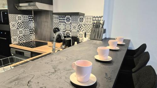 a kitchen counter with cups and saucers on it at Le Passage - Centre-ville - WiFi in Issoire
