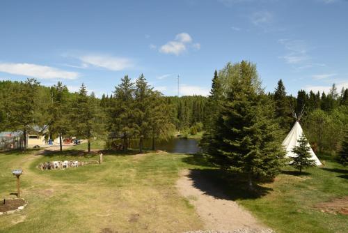 a field with a tent and a river and trees at Gîte de la Montagne Enchantée in Metabetchouan