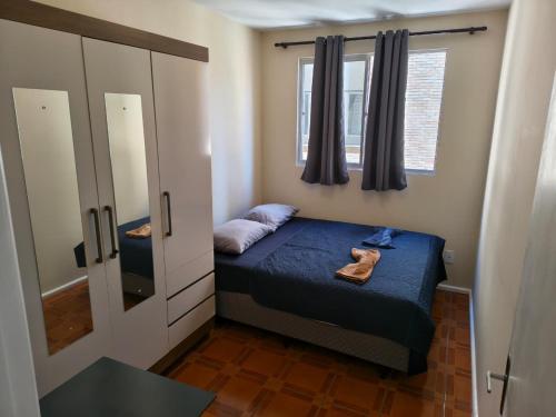 a small bedroom with a bed and a mirror at Quarto em Apartamento na Trindade in Florianópolis