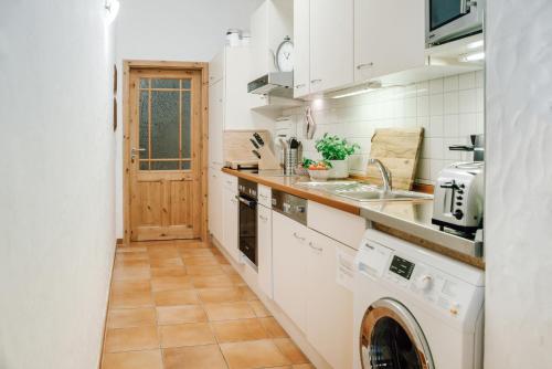 a kitchen with white cabinets and a washer and dryer at Ferienhof Werner in Emstek